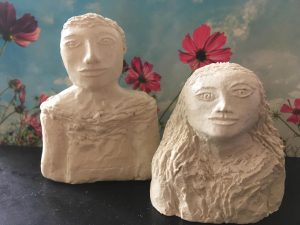 two humans in ceramics, flowers, blue sky